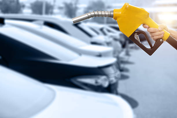 Human hand holding gasoline nozzle in the parking lot