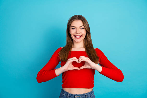 istock Cheerful Young Woman Making a Heart Shape Gesture with Her Hands in a Bright Studio Setting 2223891596