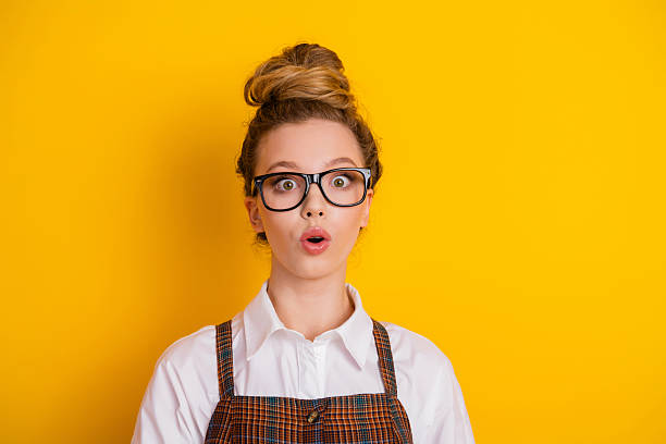 istock Surprised student wearing glasses stands against a yellow background, showcasing a cheerful and youthful expression. 2223891711