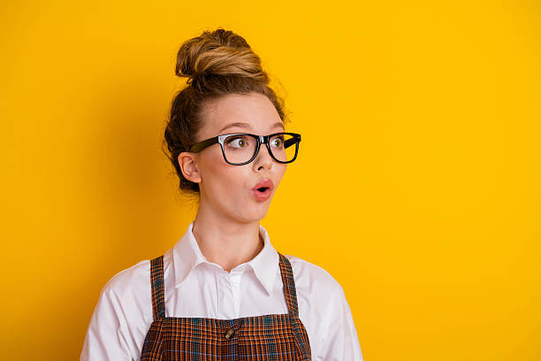 istock Young female student in stylish academic uniform with surprised expression posing against vibrant yellow background 2223891717