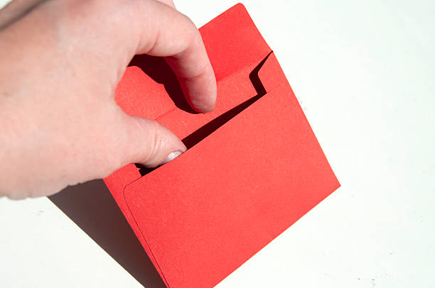 A hand holding a red envelope on white. A hand opening a little red envelope. A hand with a red envelope close-up.