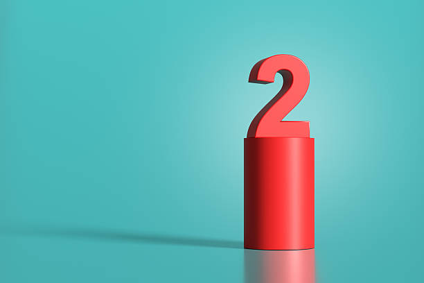 istock Red number two standing on red cylinder on turquoise background 2223893096