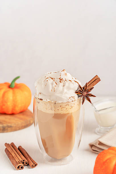 istock Pumpkin spice latte with whipped cream topping and cinnamon garnish on white table with ingredients 2223895682