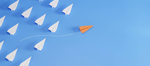 istock Orange paper plane flying in different direction from white planes on blue background. Concept of leadership, innovation, thinking differently, and standing out. 2223896826