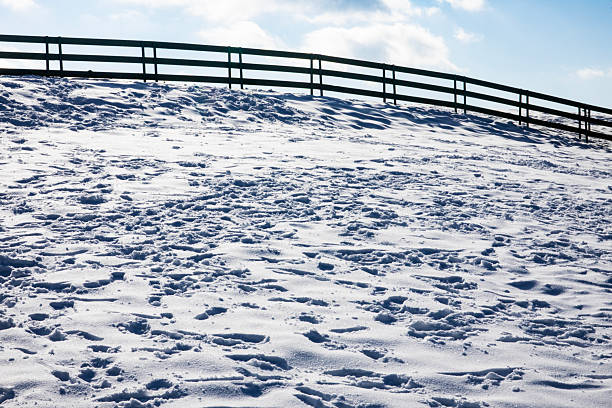 A snowy field with a fence. Outdoor. Sky. Snow. Shore. Nature