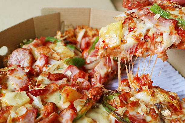Closeup of a Slice of Delectable Pizza with Stretching Cheese Being Taken from Paper Box