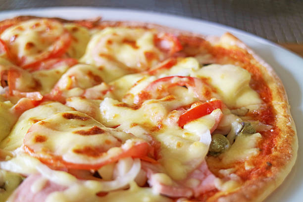 Closeup of Delectable Cheesy Ham and Tomato Pizza