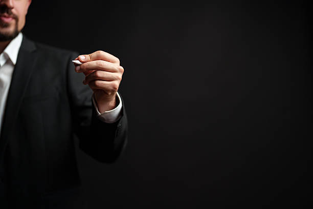 istock Business professional holds pen in formal attire while preparing for a presentation in an indoor setting at night 2223903860