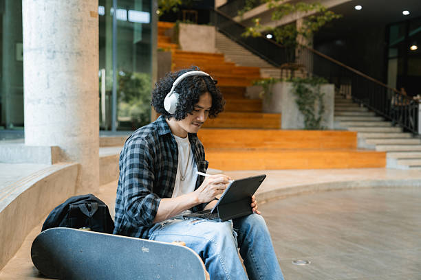 istock University students sitting in a co-working space, fully focused on his laptop as he works on his homework 2223905229