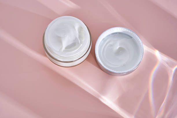 istock An open jar of cream with its texture on a pink background. 2223905464