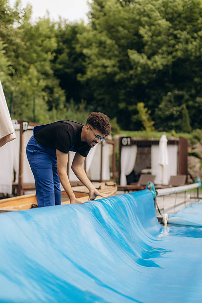 istock Pool maintenance worker covering swimming pool with thermal blanket 2223907647