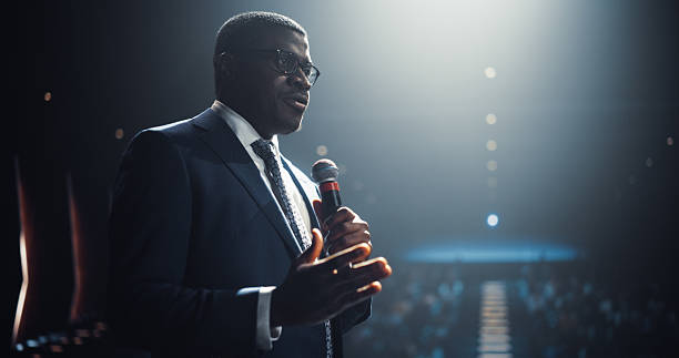 istock Tech Entrepreneur Talking Business and Venture Capital on Conference Stage. Businessman Standing with a Microphone, Wearing a Suit, Speaking About Emerging Markets at an International Business Summit 2223908310