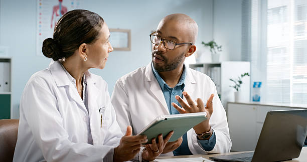 istock Doctors, discussion and team with tablet for review, problem solving and app with medical research at clinic. People, man and woman with feedback for healthcare report, solution or advice at hospital 2223908521