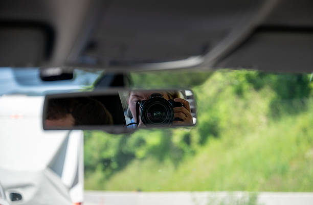 istock Photographer taking picture through rearview mirror inside car 2223909331