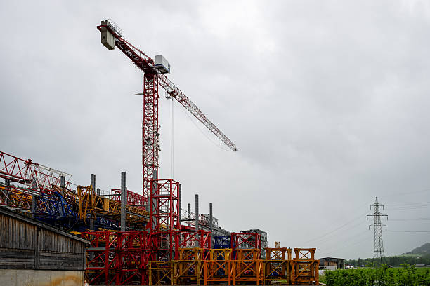 Tall red tower crane and colorful metal structures at construction equipment yard