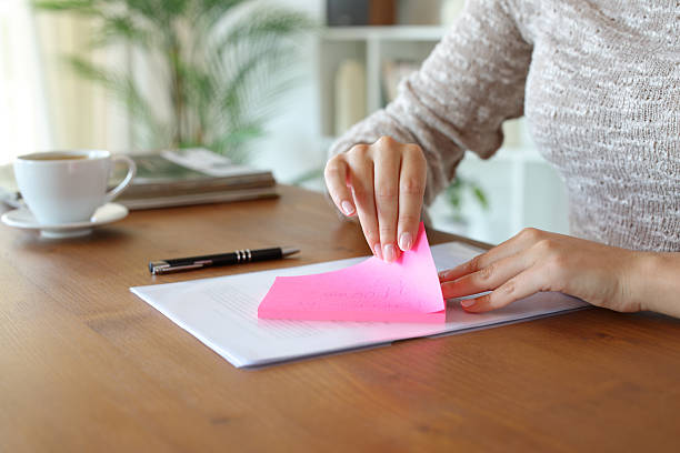 istock Woman hand removing sticky note from paper at home 2223912779
