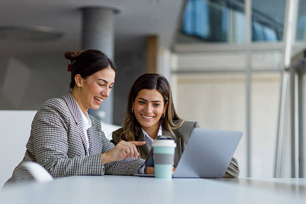 istock Two young businesswomen are collaborating on a project, pointing at a smartphone screen and using a laptop in a modern office environment 2223914458