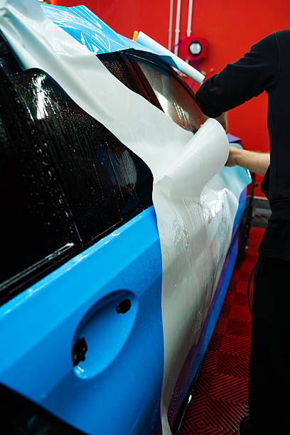 istock Protective film layering during PPF wrap detailing to protect the car surface from scratches and UV. Wet PPF Wrapping on Car Panel in detailing center. 2223914556