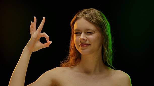 istock Young Woman Showing Okay Gesture in Subtle Lighting 2223915137