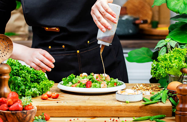 istock passionate chef artfully prepares colorful vegetable salad while drizzling dressing in bright kitchen filled with greenery. 2223917523