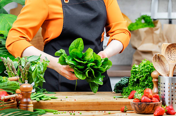 istock Chef woman prepares spinach, fresh greens and vegetables in a modern kitchen, showcasing her dedication to healthy vegan recipes and cooking techniques. 2223917549
