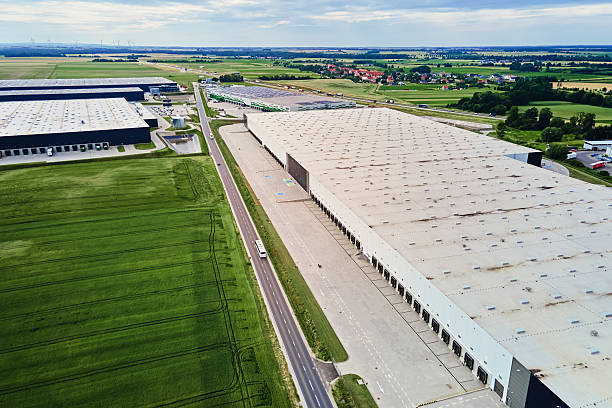 istock Large modern warehouse with loading docks in green rural landscape 2223924087