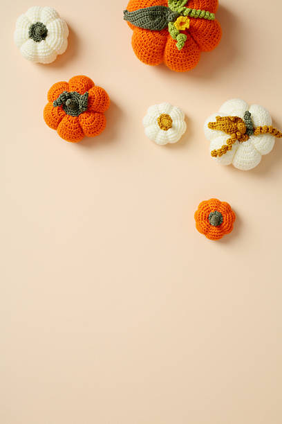istock Set of crocheted pumpkins and a flower on peach backdrop 2223924737