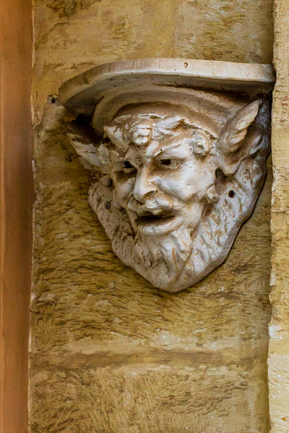 Detailed image capturing a mythological face ornament on a stone wall, showcasing artistry.