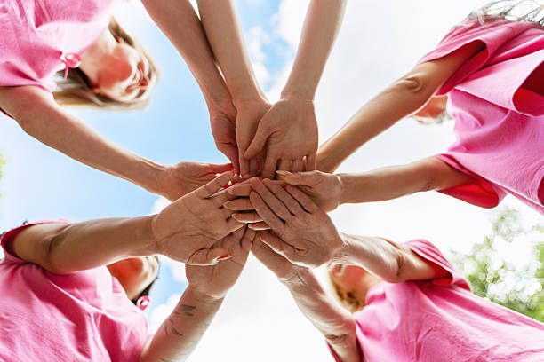 istock Women joining hands for breast cancer awareness, showing unity and support 2223933241