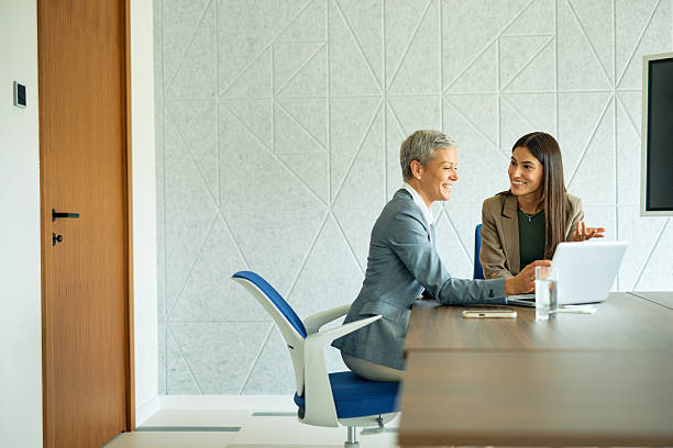 istock Two businesswomen smiling and discussing work in modern office 2223934349