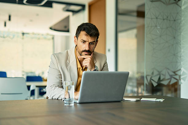 istock Pensive businessman working on laptop in modern office 2223934502