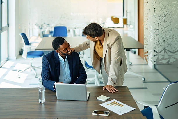 istock Two smiling businessmen working together in modern office using laptop 2223934580
