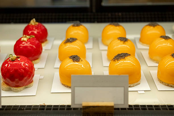 Orange and red dome-shaped pastries with glossy glaze on display. Close-up gourmet dessert photography