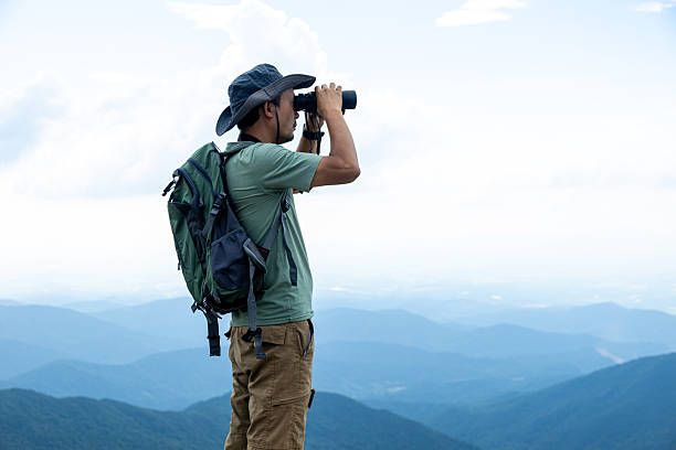 istock Traveler backpacker looking through telescope on top of mountain 2223942106