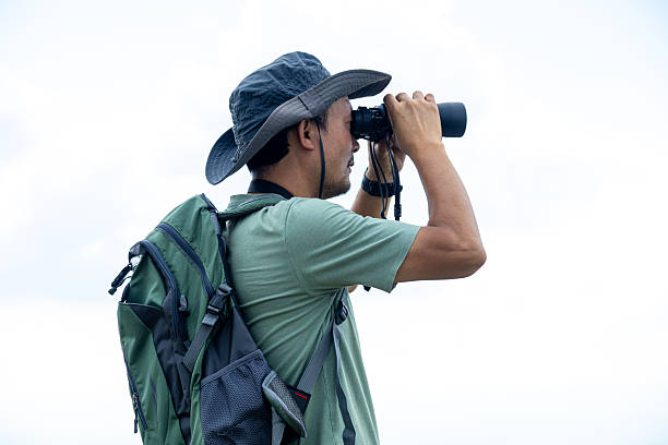 istock Traveler backpacker looking through telescope on top of mountain 2223942167