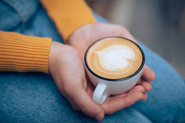 Woman holding a fresh cup of coffee with froth art.