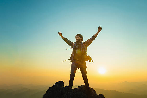 istock man is standing on a mountain top, looking out at the horizon 2223946328