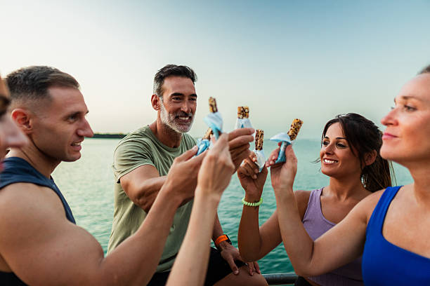 Fitness group sharing energy bars by the sea