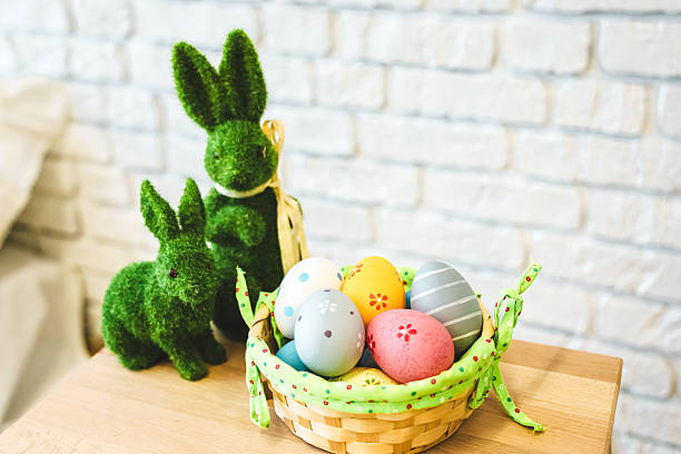 istock Colorful Easter eggs in a basket with decorative bunnies on a wooden table 2223962697