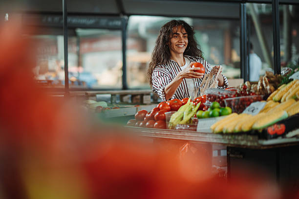 istock Smiling vendor arranging fresh produce at market 2223962937