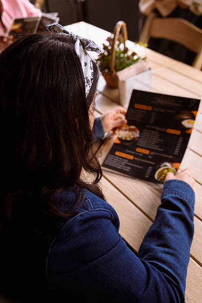 istock Unrecognizable woman looking at a restaurant menu 2223967424