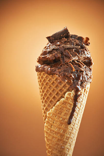 A hand holding a couble scoop ice cream cone isolated on yellow