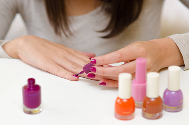 Beautiful young woman painting her fingernails at home.