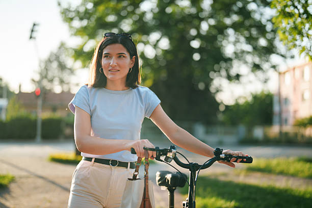 istock Young Woman Walking with Bicycle in the Park 2223978564