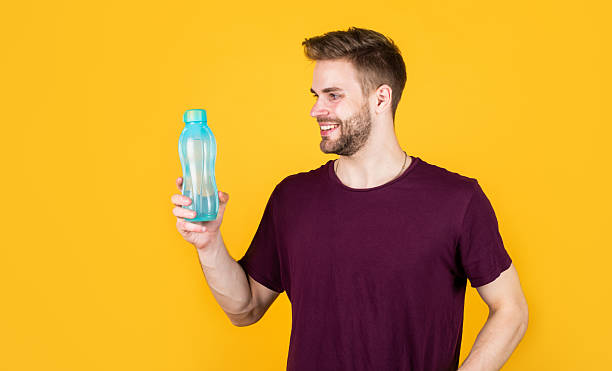 istock handsome young man in shirt drink water from bottle, hydration 2223979484
