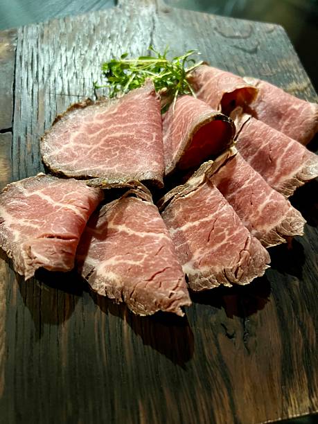 Thinly sliced roast beef arranged on a wooden board