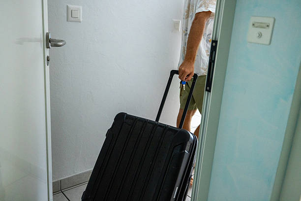 istock Man Entering Room with Black Rolling Suitcase 2223988336