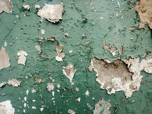 Close-up of a distressed green wall with peeling paint, revealing the underlying surface