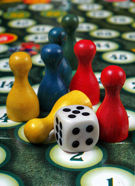 istock colorful play figures with dice on board 2223989654