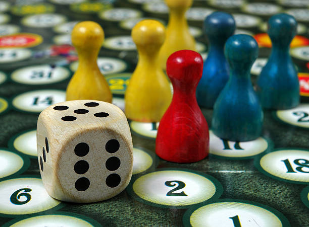 istock colorful play figures with dice on board 2223993275